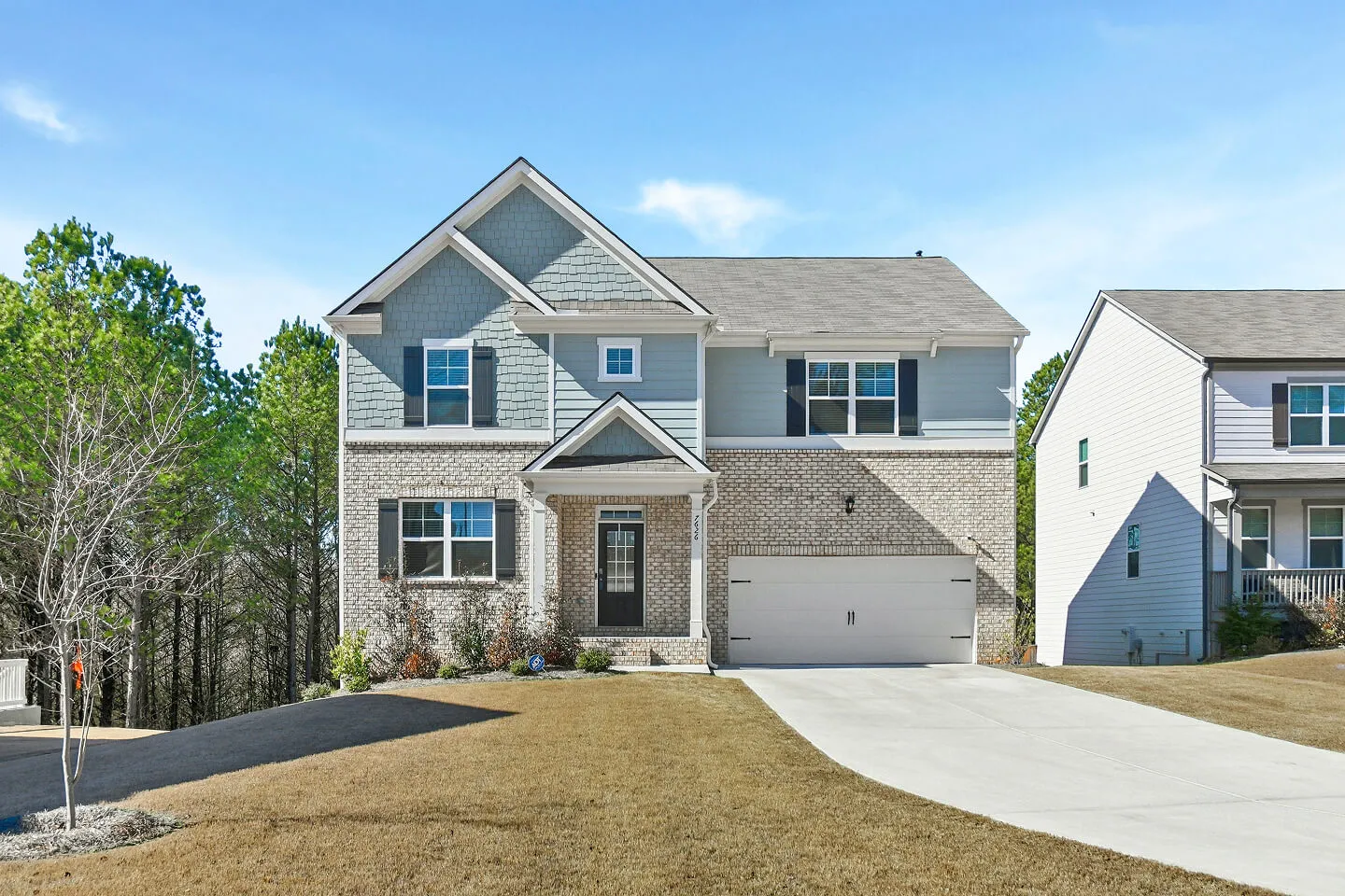 Two-story home with a brick and blue siding facade, covered entry, and two-car garage